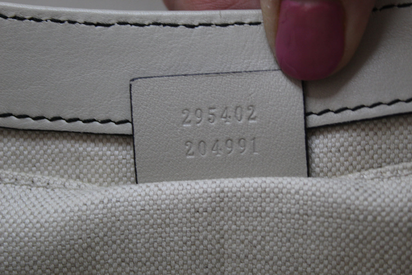 Gucci serial code Close-up of a grey fabric surface with a label displaying numbers.