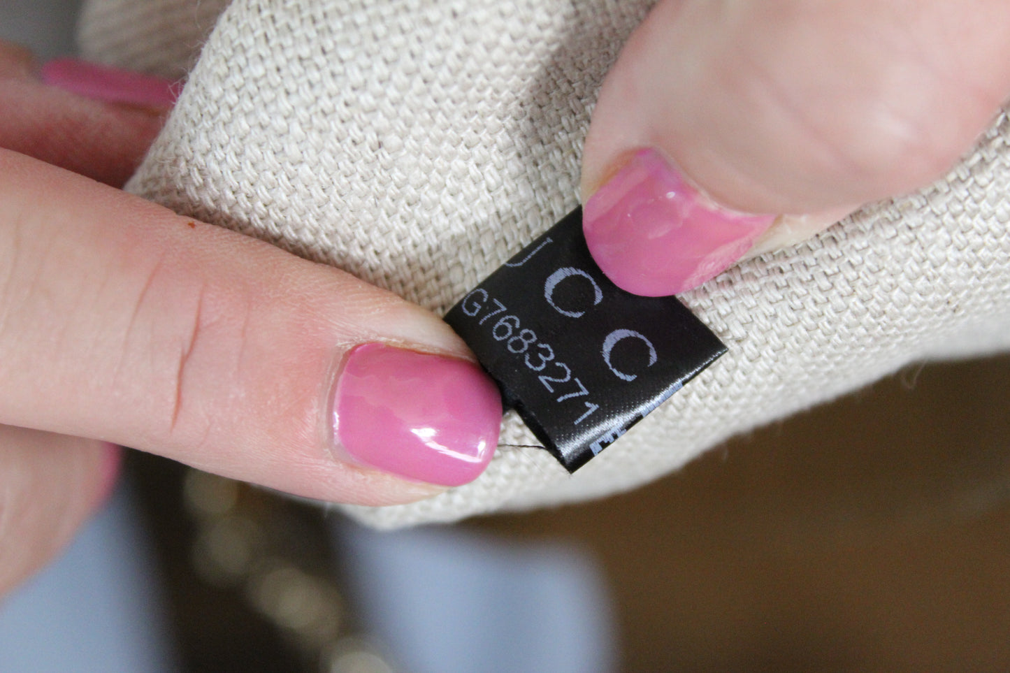 Close-up of a hand holding a fabric item with a label featuring 'CC' initials.