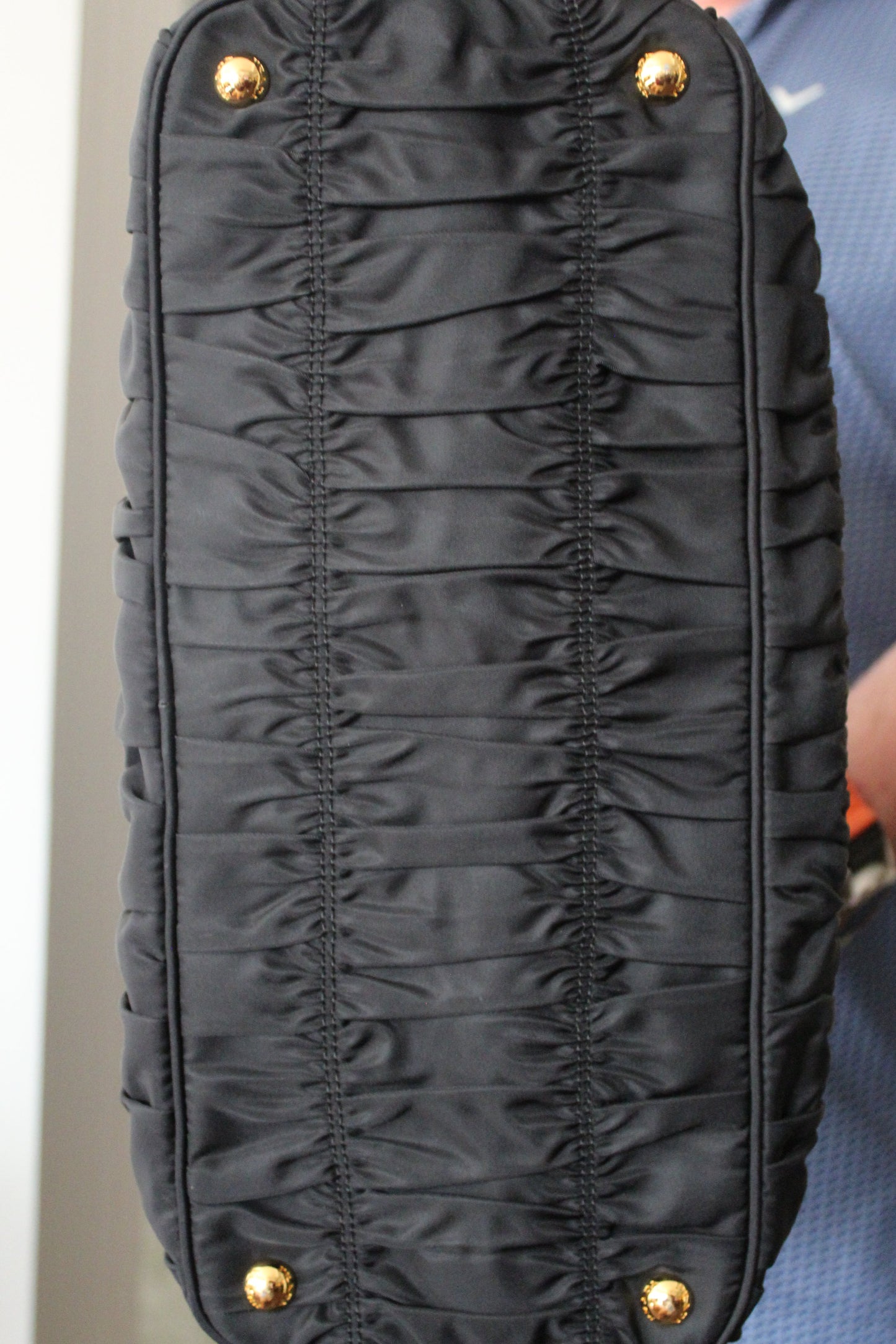 Botton/Black quilted handbag with gold accents held by a person