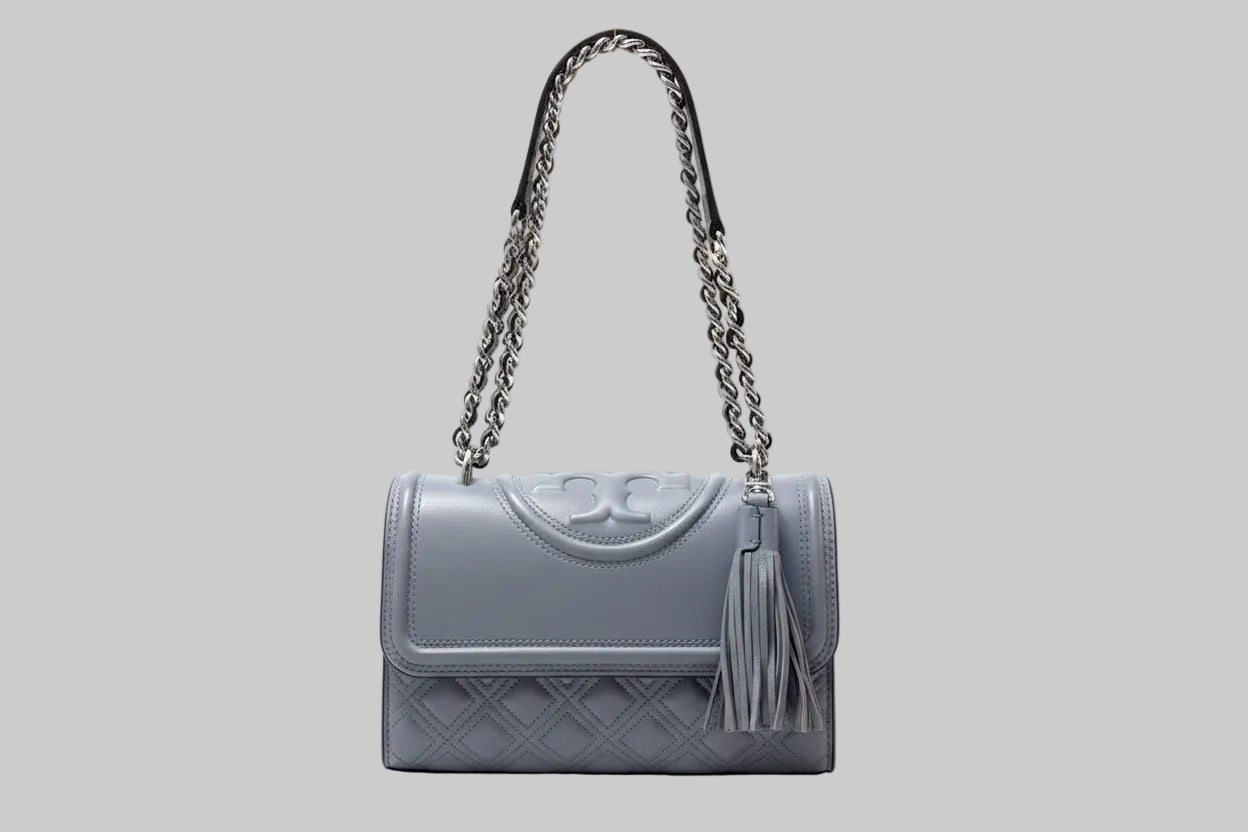 Tory Burch Gray/Blue quilted handbag with a silver chain strap on a light gray background