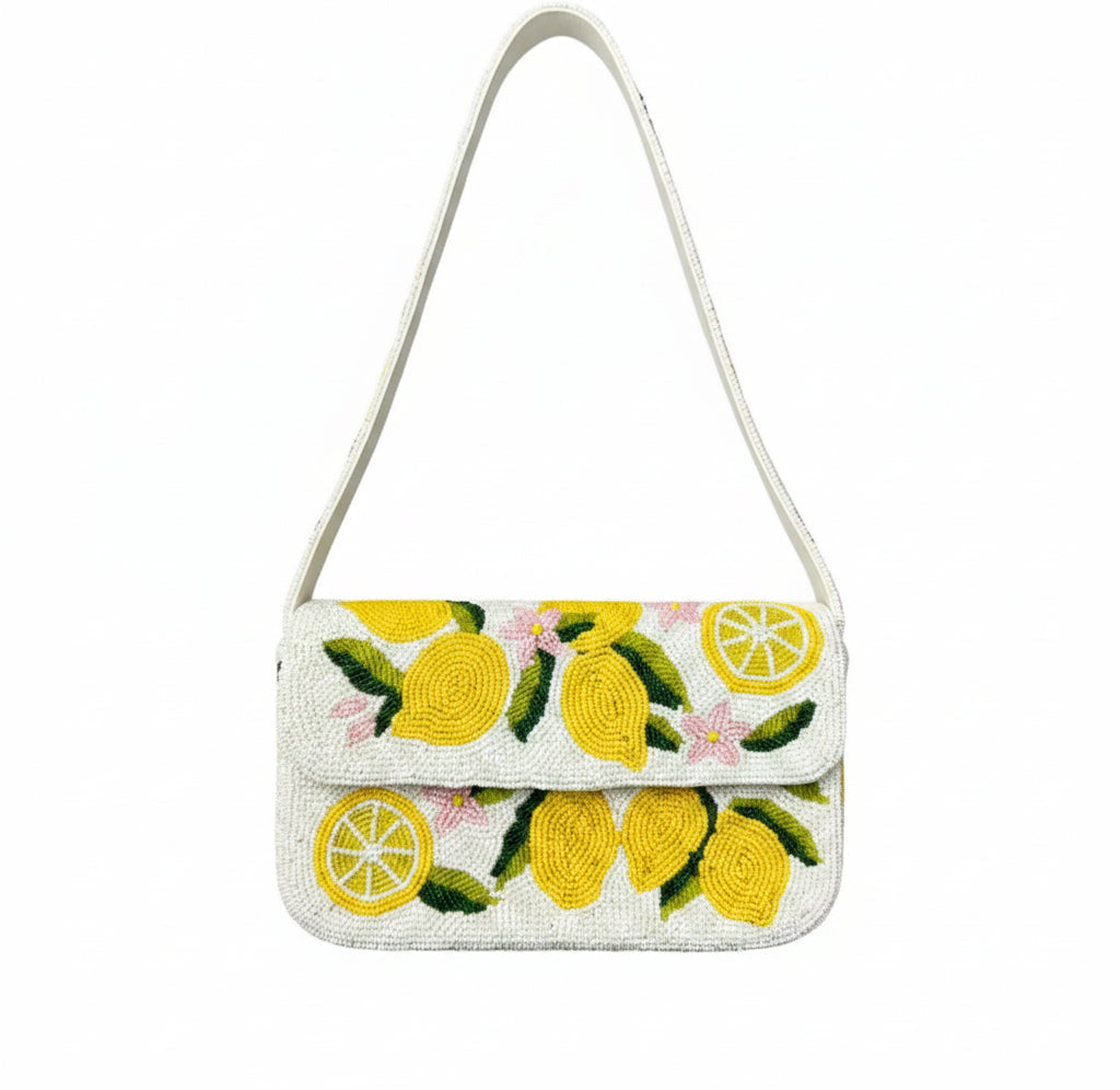 A white beaded shoulder bag with a yellow lemon and green leaf pattern, featuring a white shoulder strap, shown against a white background with black letterboxing.