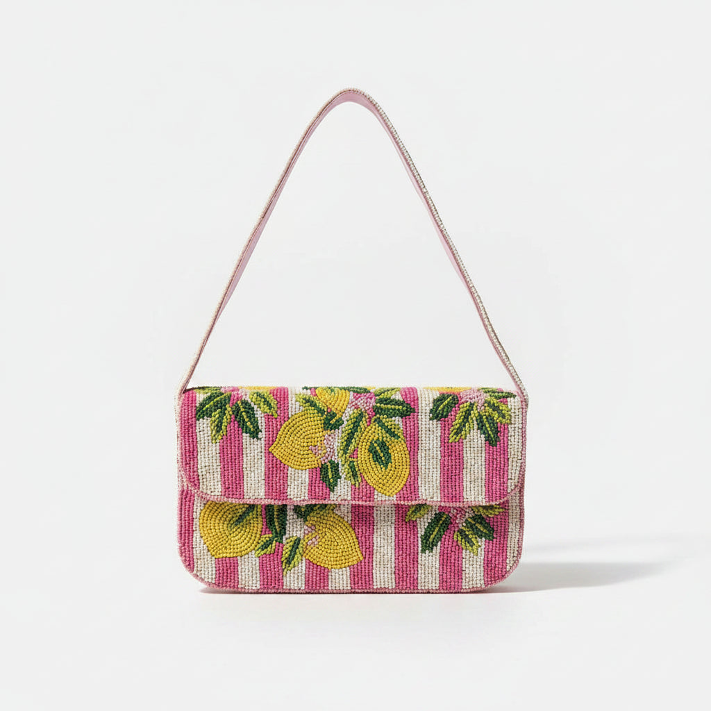 A small rectangular handbag with a pink and white striped body, decorated with yellow and green beaded lemon motifs, featuring a pink shoulder strap.