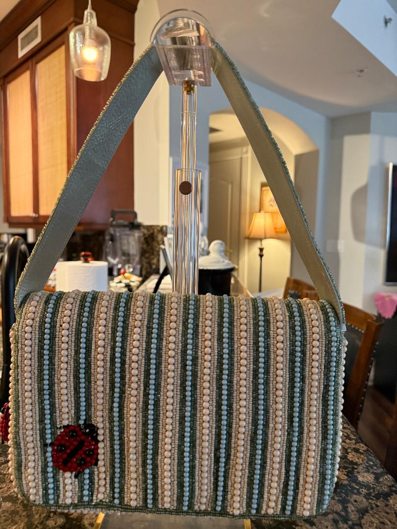 Striped handbag with a ladybug charm in an indoor setting