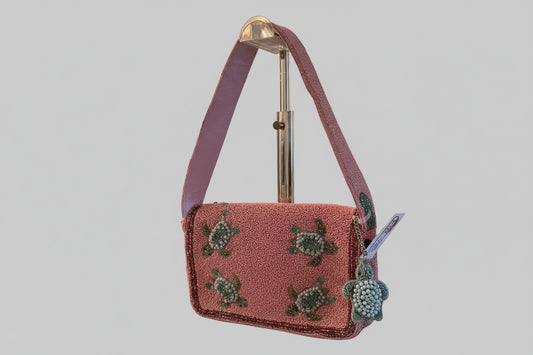 Pink beaded handbag with turtle design on a kitchen counter