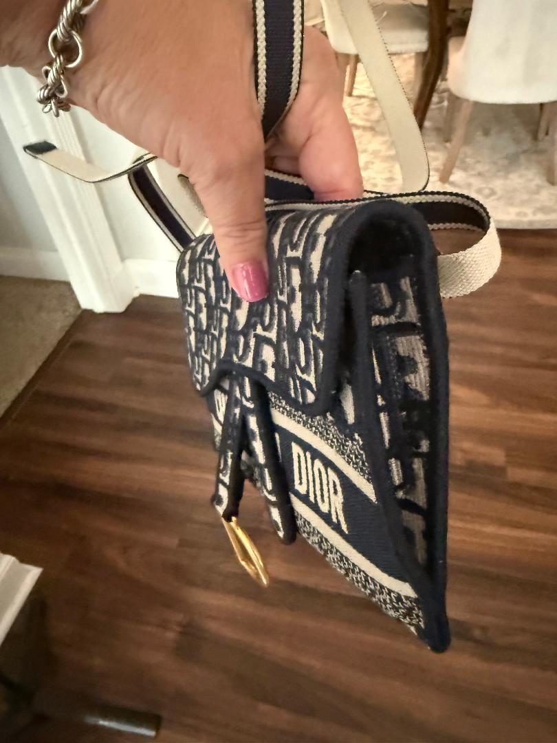 Small Dior bag held by a hand on a wooden floor