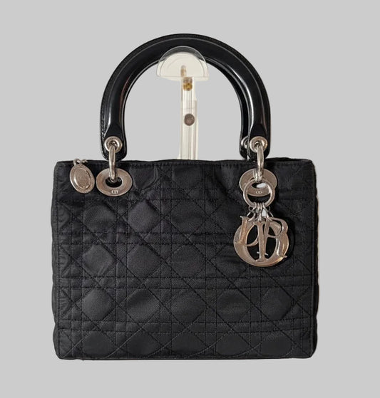 Lady Dior Black quilted handbag with silver  DIOR hardware on a gray background