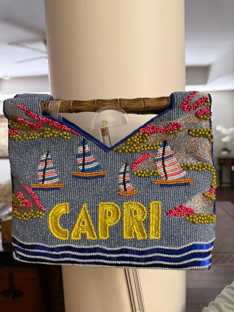 Decorative handbag with 'Capri' text and sailboat designs on a mannequin.