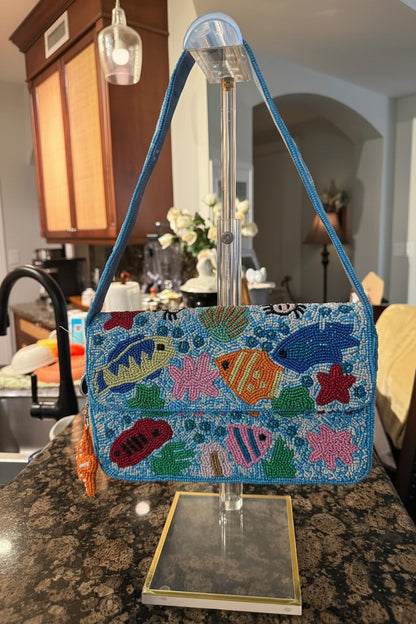 Colorful beaded handbag with fish design on a stand in a kitchen setting