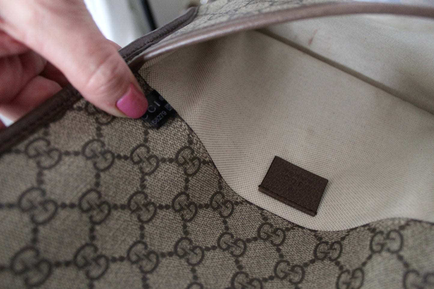 Close-up of a patterned fabric with a brand label, held by a hand.