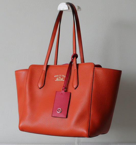 Gucci orange leather handbag with a visible brand logo on a gray background