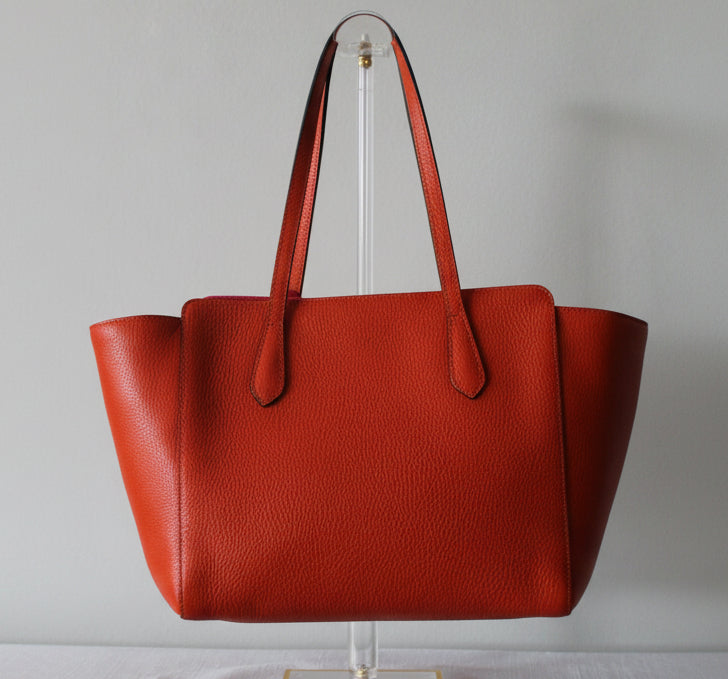 Gucci orange leather tote bag on a gray background