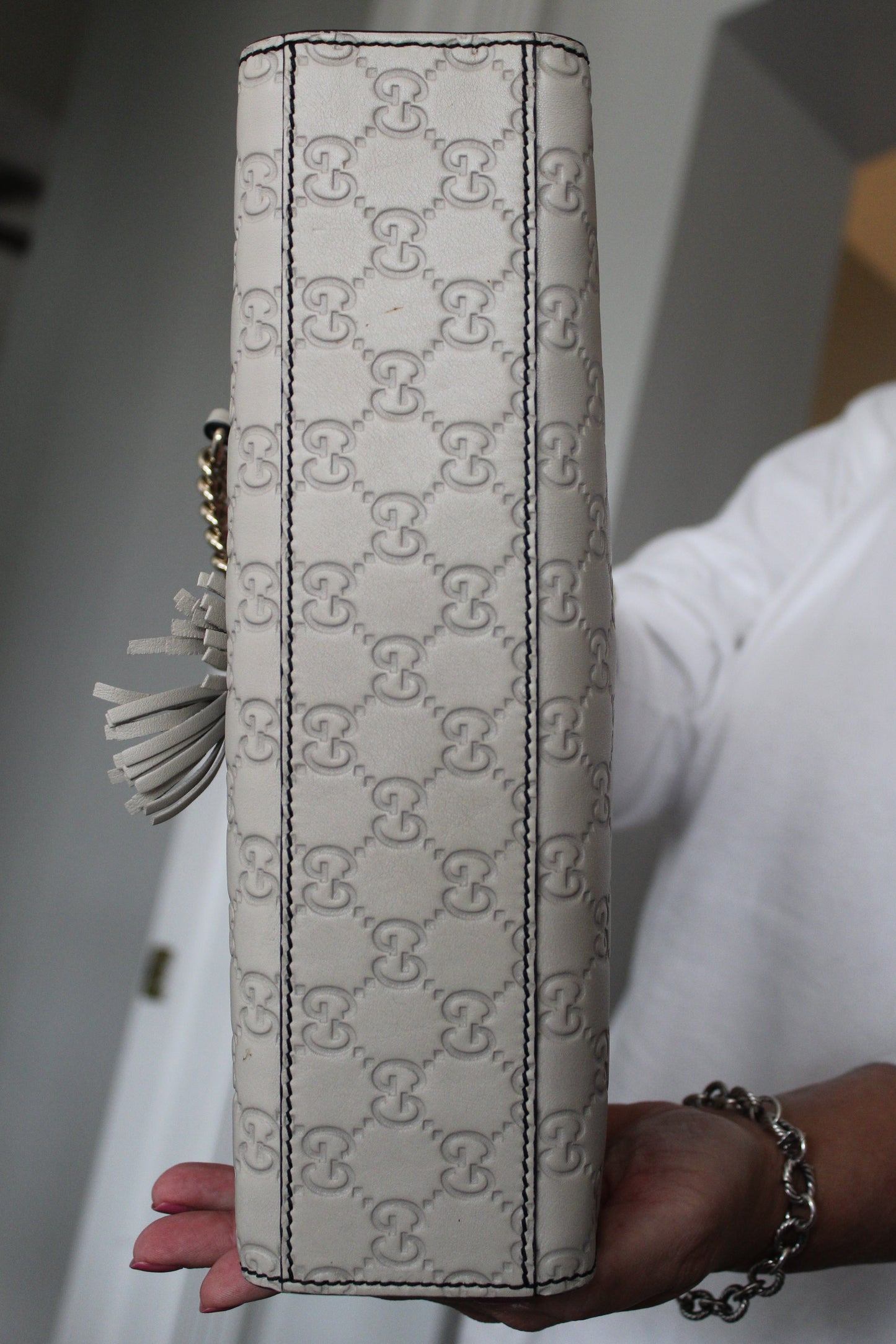 Gucci grey handbag held by a person with a neutral background