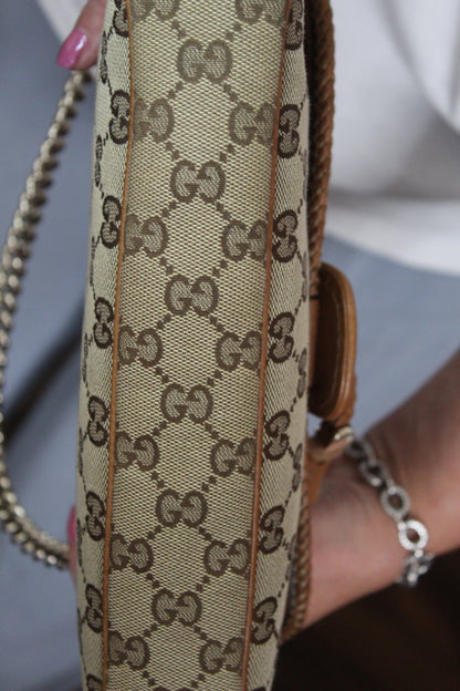 Close-up of a hand holding a Gucci handbag with a blurred background