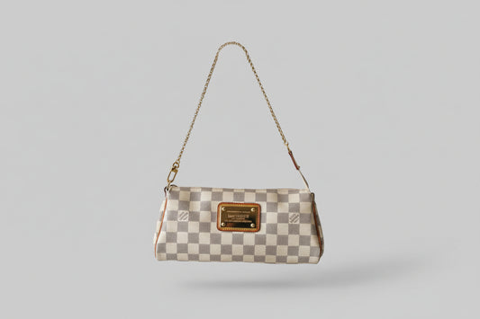 Designer handbag with checkered pattern and brand logo on a stand against a gray background