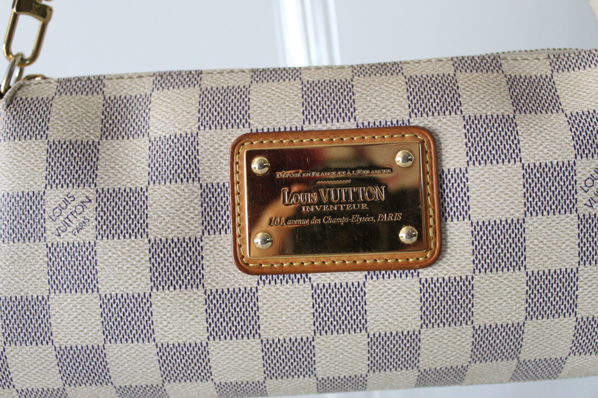 Louis Vuitton handbag with checkered pattern and brand logo on a white background