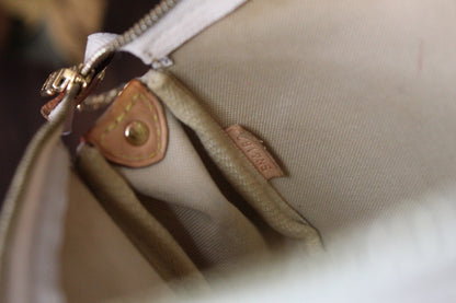 Close-up of a beige handbag with a gold zipper and visible brand logo.