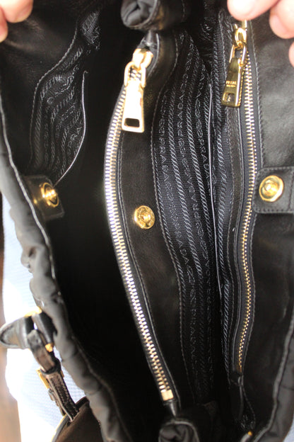 Close-up of a black leather handbag with gold zippers and hardware.