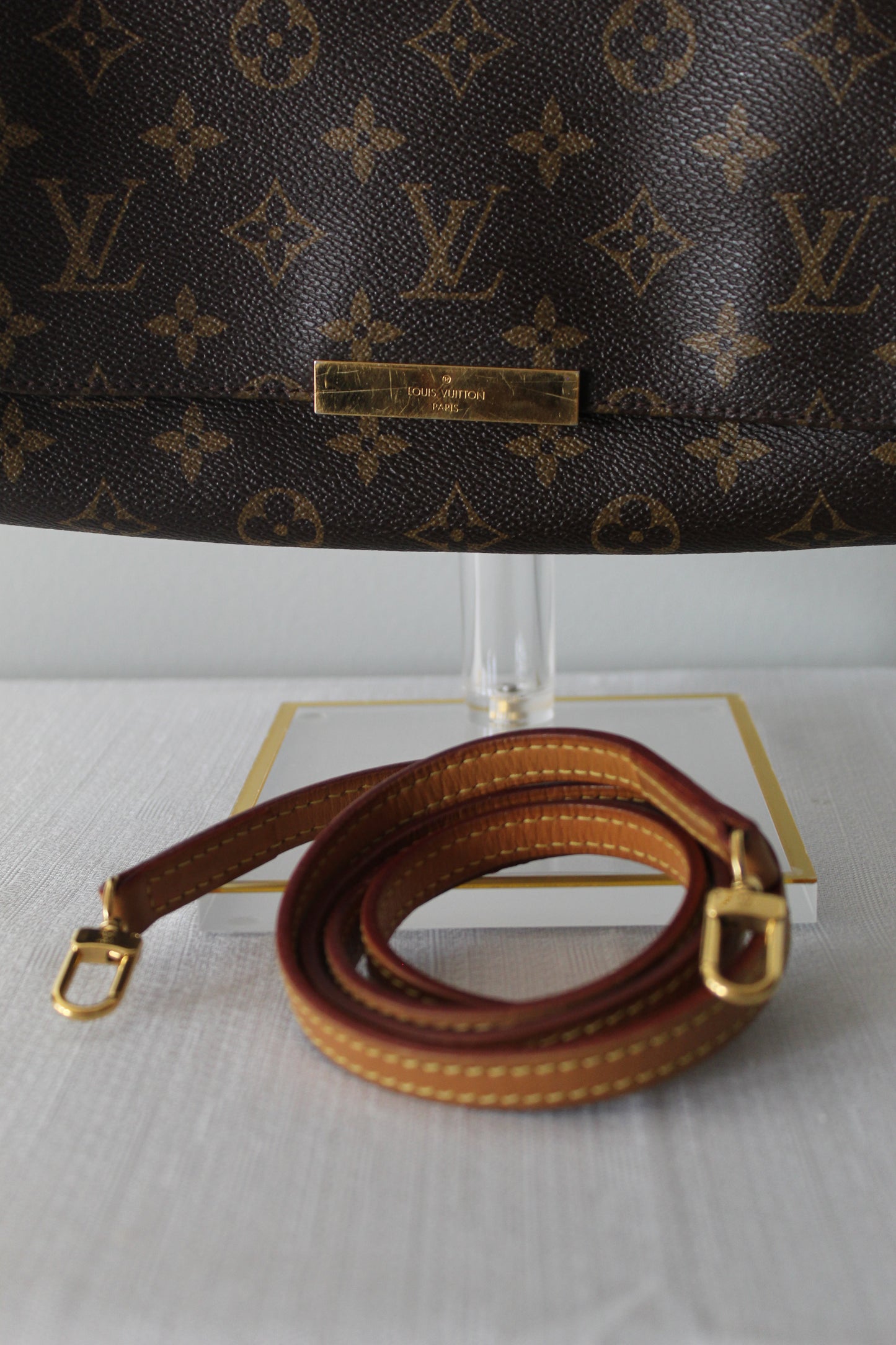 Louis Vuitton monogram handbag with brown leather strap on a white background