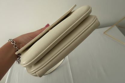 White/Cream crossbody held by a hand with a white background