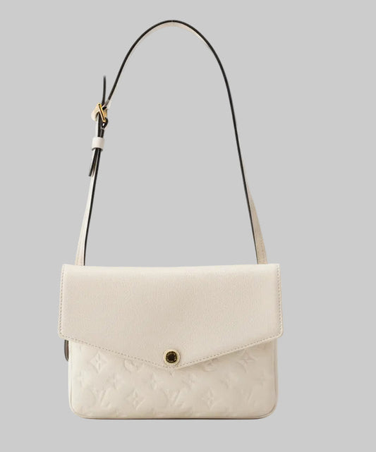 Louis Vuitton White mono envelope handbag with a gold clasp on a gray backgroundi