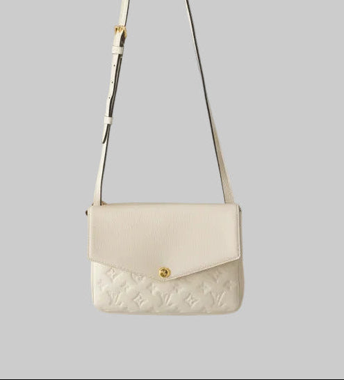 Louis Vuitton Cream envelope  handbag with a monogram on a light gray background