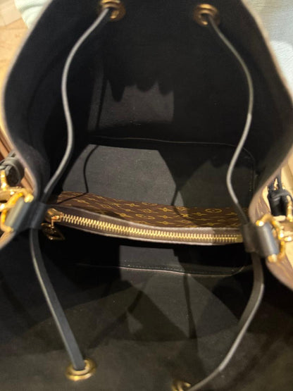 Close-up of a black handbag with gold accents on a reflective surface