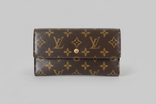 Louis Vuitton wallet with monogram pattern on a stand against a gray background