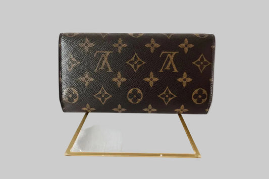 Louis Vuitton wallet on a stand with a gray background