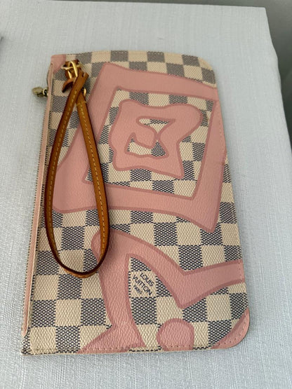 Designer handbag with checkered pattern and pink rose design on a light gray surface