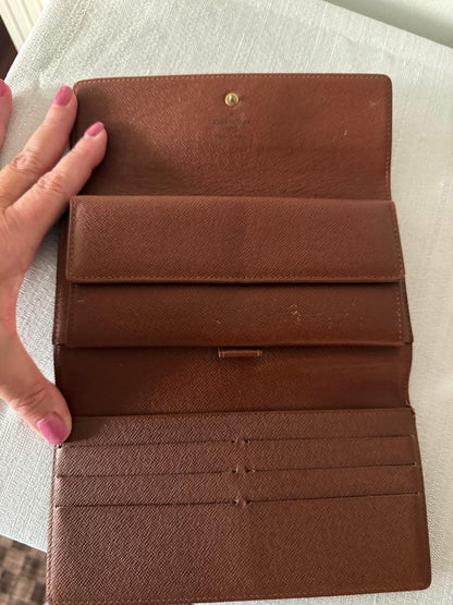 Louis Vuitton Brown wallet with visible wear on a white surface