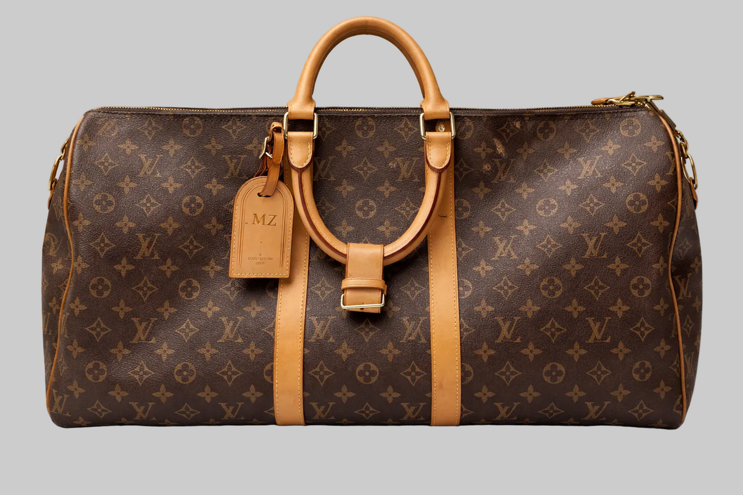 Brown leather bag with tan handles and strap on a gray background