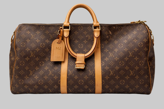 Brown leather bag with tan handles and strap on a gray background