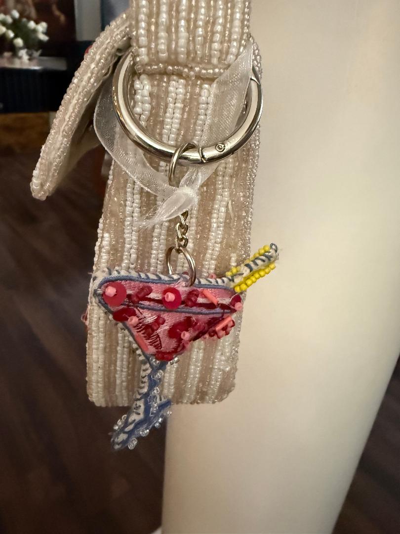 Keychain with a martini glass charm attached to a beaded bag.