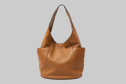 Tory Burch Brown leather handbag with side pockets on a gray background