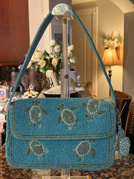 Blue handbag with turtle designs on a stand in a room setting