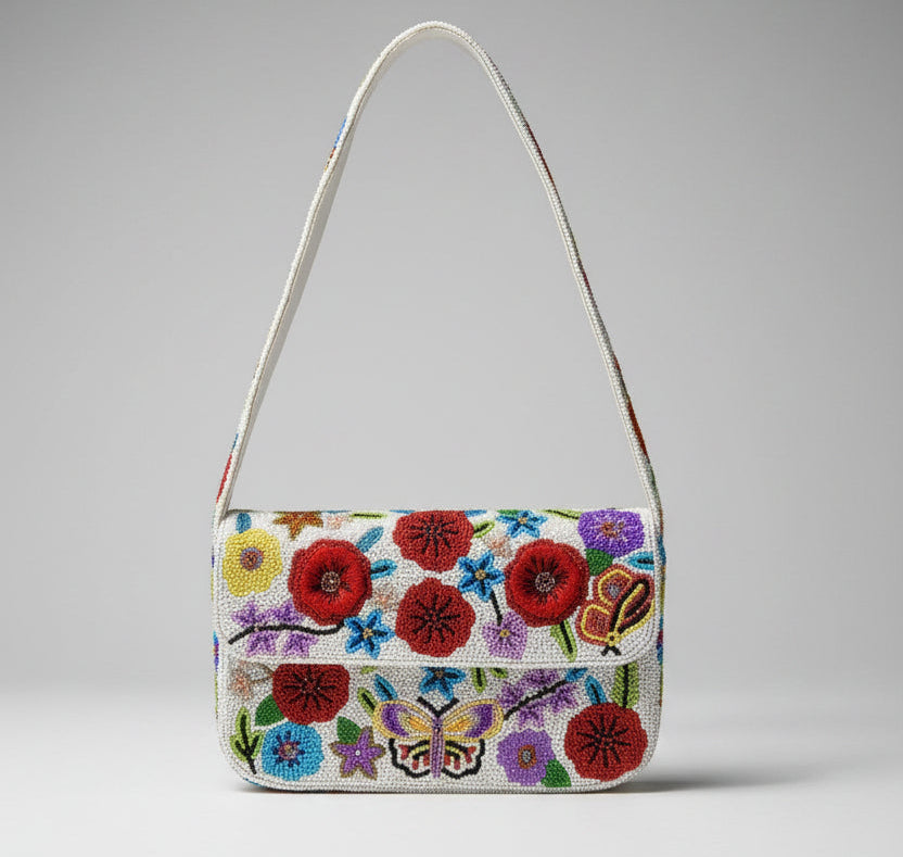 A small white shoulder bag with a flap closure, decorated with colorful embroidered flowers and a butterfly motif, shown against a plain white background.